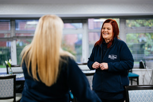 Two female colleagues wearing Be One Homes fleeces. One colleague is smiling at the other.