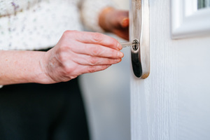 Woman inserting a key into a front door.