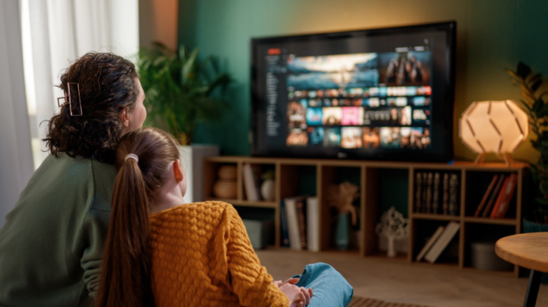 A woman and young girl sat in a living room watching TV together.