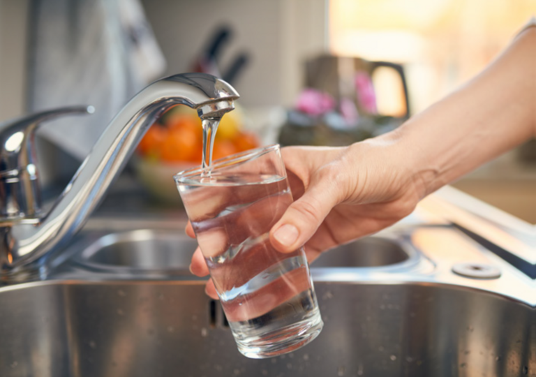 A glass of water being filled at using a kitchen tap.