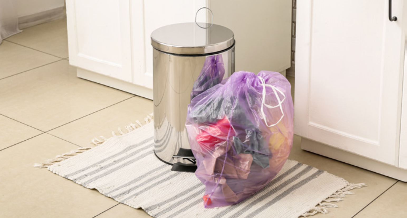 A bag of rubbish placed next to a bin.