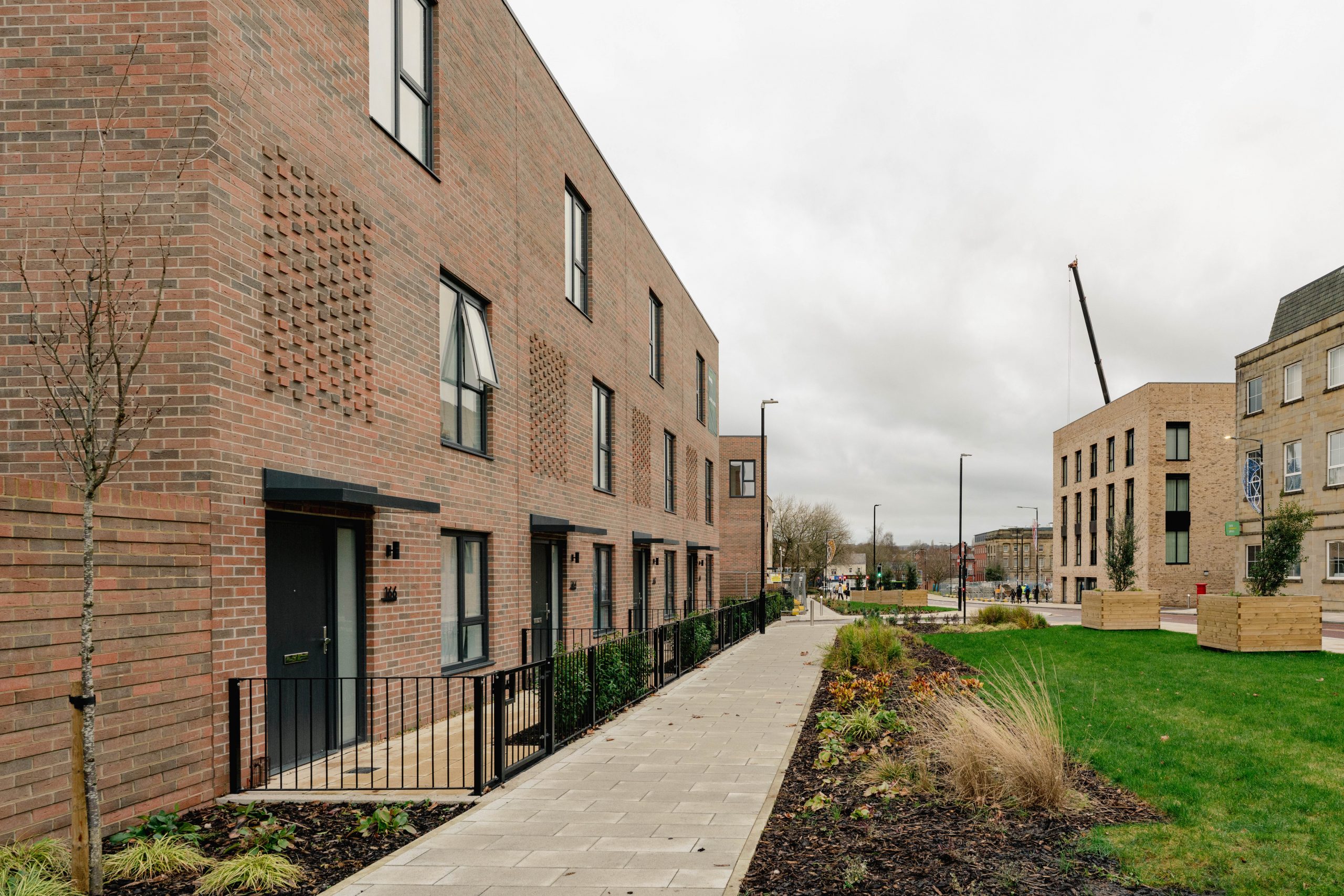 A row of houses at our Moor Lane development in Bolton Town Centre. There is a patch of grass running parallel to the path in front of the houses.