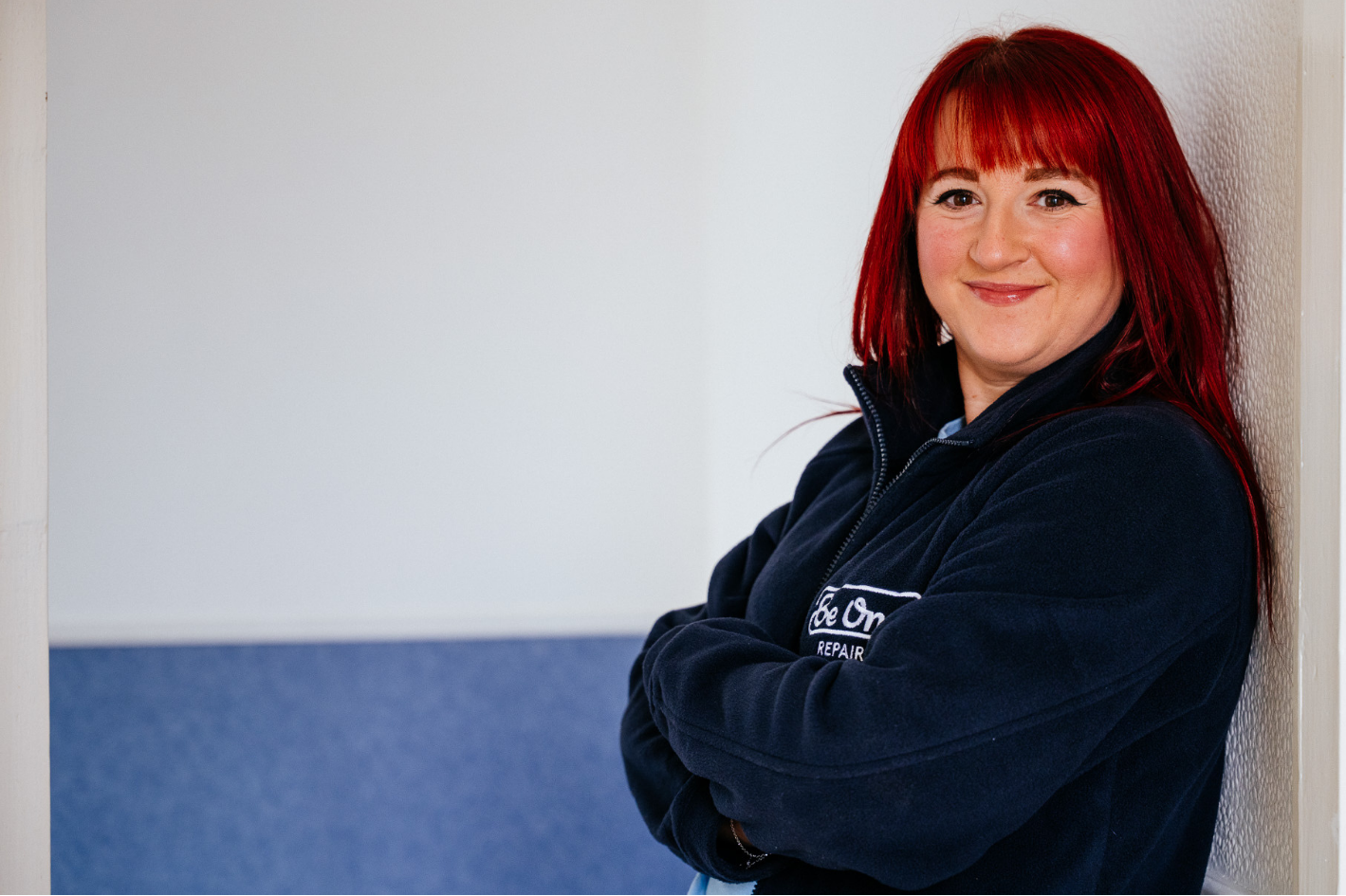 A female Be One Homes colleague stood with her arms folded. She is wearing a blue Be One Homes fleece.