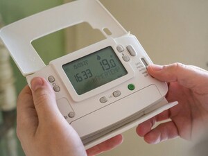 A wireless control unit for a central heating system. Someone is holding the unit as they adjust the temperature.