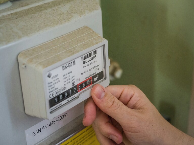 An energy meter, with the readings visible. Someone is touching the meter with their thumb as they take a reading.