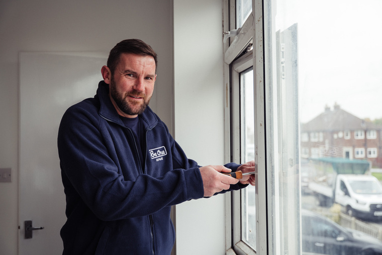 A male Be One Repairs operative using a screwdriver to fix part of a window frame.