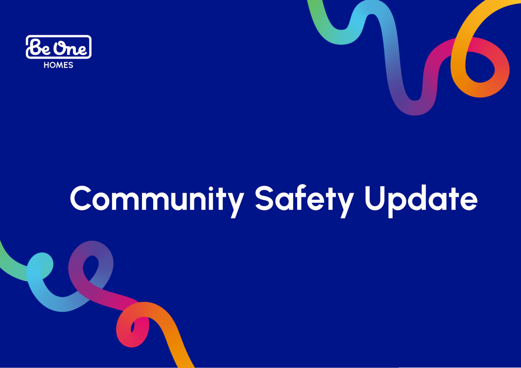 Be One Homes branded graphic with a dark blue background, featuring the Be One Homes logo in the top left and the text “Community Safety Update” in large white lettering. Colourful curved ribbon shapes in green, blue, pink and orange appear around the edges.