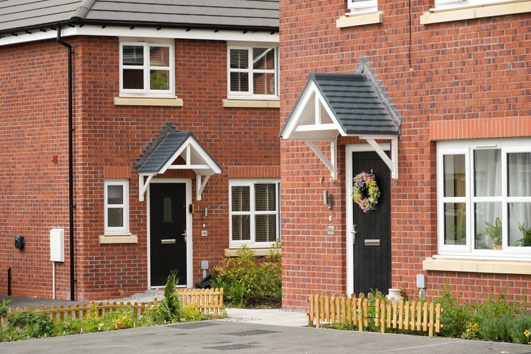 Two affordable homes at Inverbeg Drive with front gardens and entrances visible.