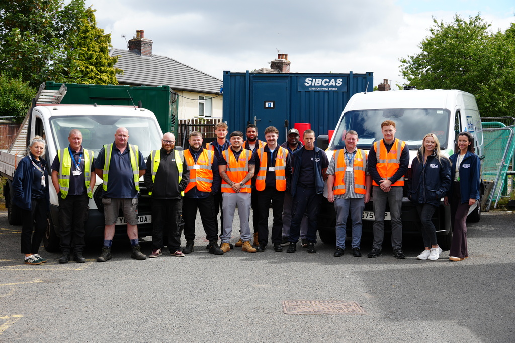 A group photo of colleagues and partners involved with our Platt Hill retrofit project. they are stood in front of BAAS Construction and Be One Homes vans.