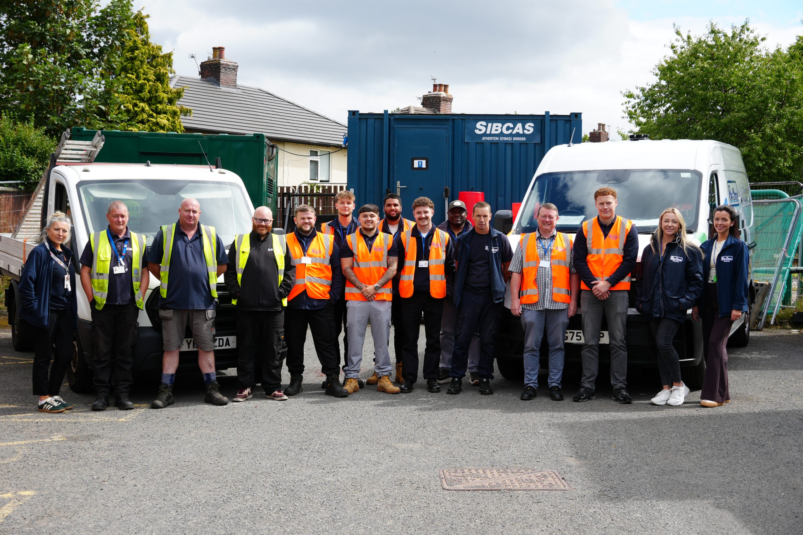 A group photo of colleagues and partners involved with our Platt Hill retrofit project. they are stood in front of BAAS Construction and Be One Homes vans.