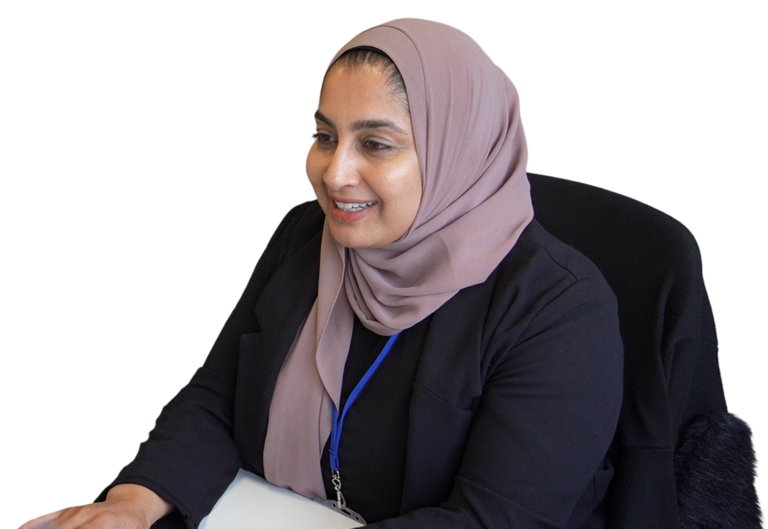 A female Be One Homes colleague working at her desk. She is using a keyboard and smiling.